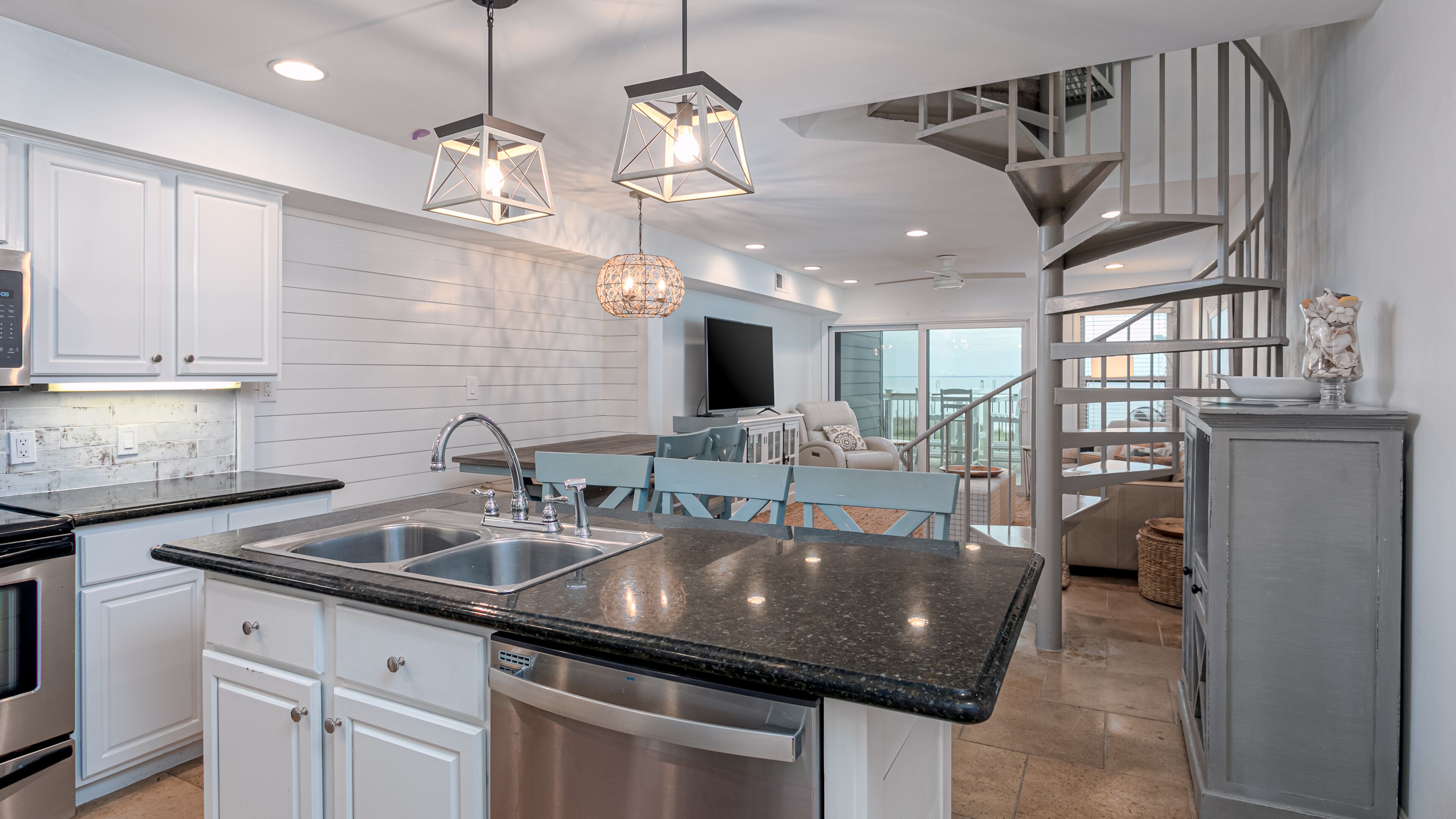A modern kitchen with a central island, stainless steel appliances, and a dining area with a view.