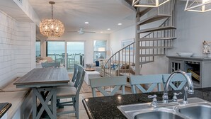 A modern kitchen with a granite countertop, stainless steel sink, and a staircase leading to a balcony. - Spacious condo with sleeping loft - Sleeps 10 on Pensacola Bay - San Deluna 29 (Pensacola Beach)