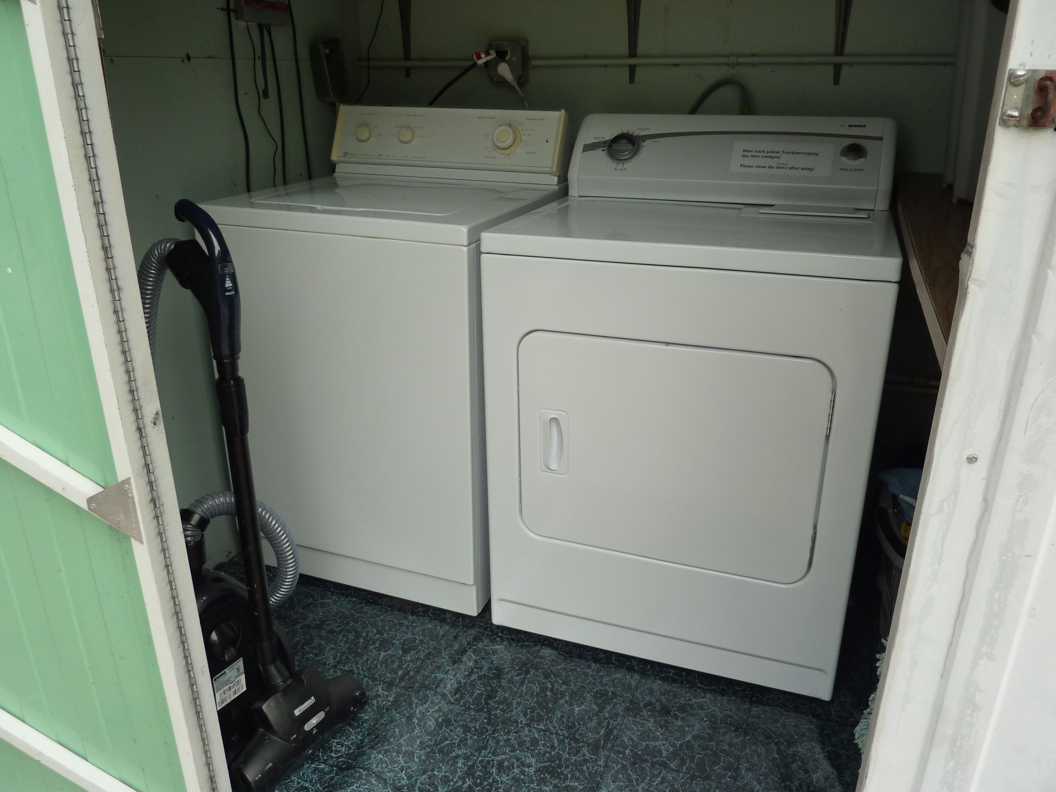A laundry area with two white washing machines and a vacuum cleaner.
