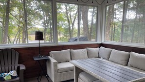 A cozy seating area with a cushioned bench and a table, surrounded by large windows offering a view of trees. - Couples Retreat, NEW Hot Tub 2022, ORV, Right From the Front Door (Baldwin)