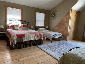A bedroom with two beds, wooden flooring, a sloped ceiling, and a wooden door. - Couples Retreat, NEW Hot Tub 2022, ORV, Right From the Front Door (Baldwin)
