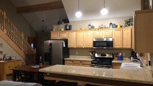 A kitchen with wooden cabinets, a refrigerator, a microwave, and a stove. There is a dining area with a table and chairs. - Couples Retreat, NEW Hot Tub 2022, ORV, Right From the Front Door (Baldwin)