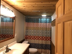 A bathroom with a wooden ceiling, a patterned shower curtain, a white sink, and a toilet. - Couples Retreat, NEW Hot Tub 2022, ORV, Right From the Front Door (Baldwin)