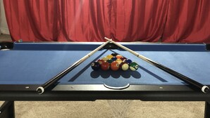 Een biljarttafel met een rode gordijnachtergrond.