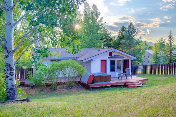 A small, single-story house with a red door and a covered porch.