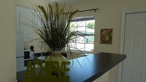A kitchen with a black countertop, a decorative plant in a vase, and a 'ACHIEVE' sign.