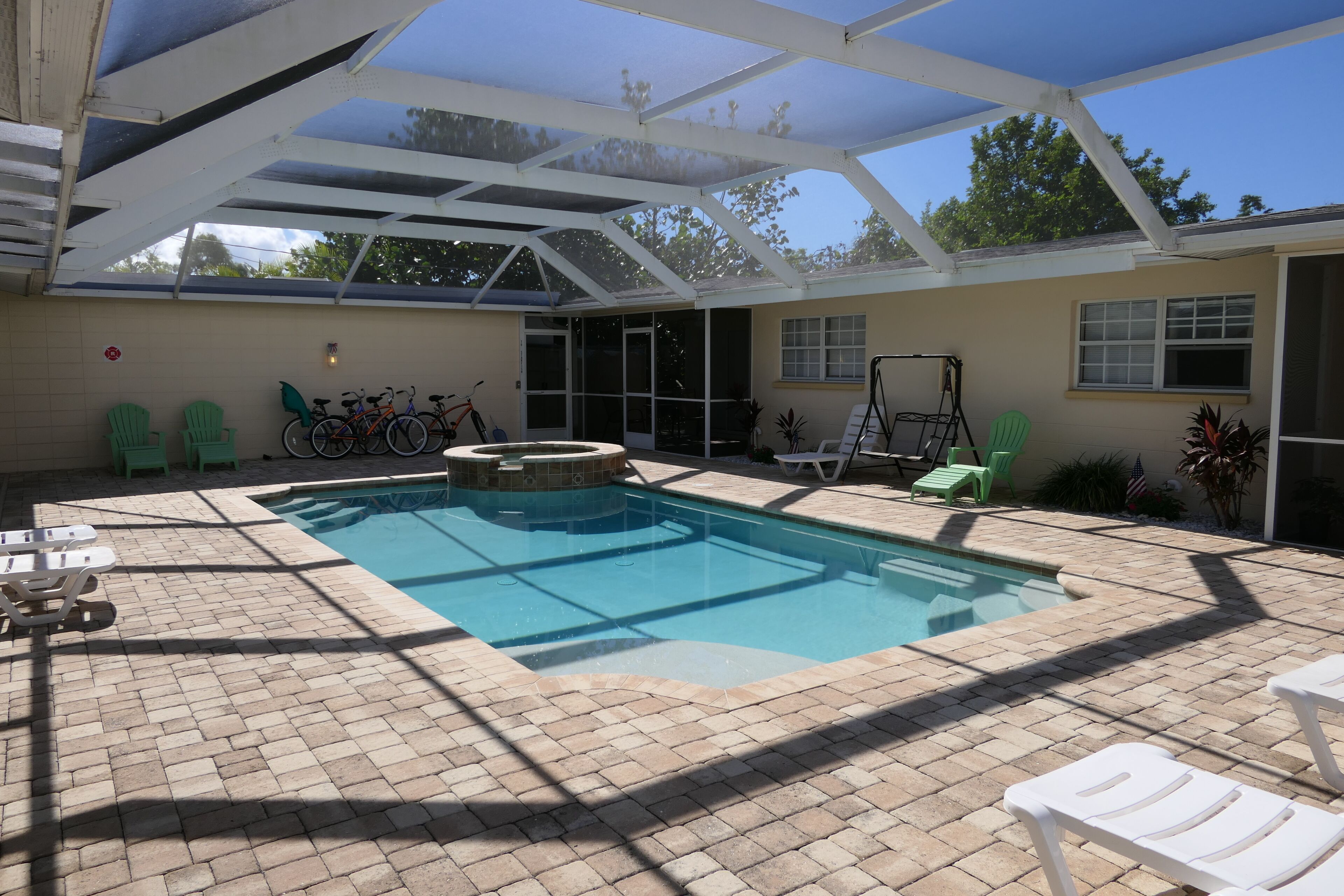 A covered outdoor swimming pool with a patio area, seating, and a bicycle rack.