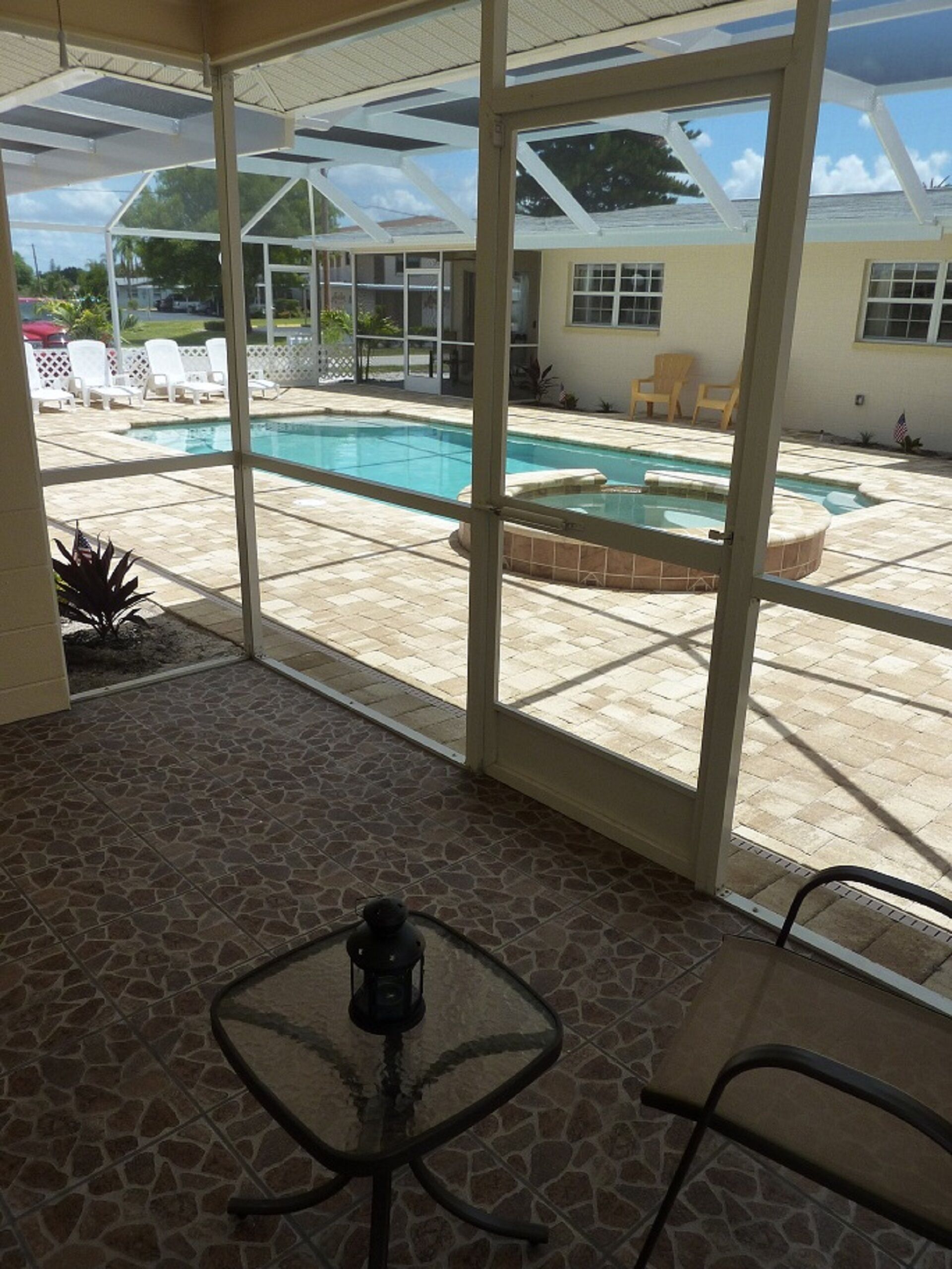 Una veranda coperta con piscina, sedute all'aperto e un tavolo con una lanterna.