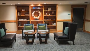 Un vestíbulo con mostrador de recepción, dos sillones con cojines, una estantería de madera y un adorno circular en la pared.