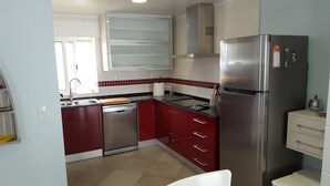 Eine moderne Küche mit roten Schränken, Edelstahlgeräten und einer gefliesten Spritzschutzwand.