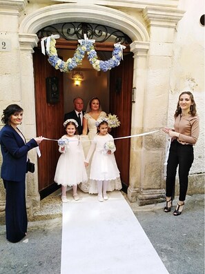 Une entrée d’immeuble avec une porte blanche, une plaque portant le numéro « 2 » et une guirlande décorative au-dessus de la porte.