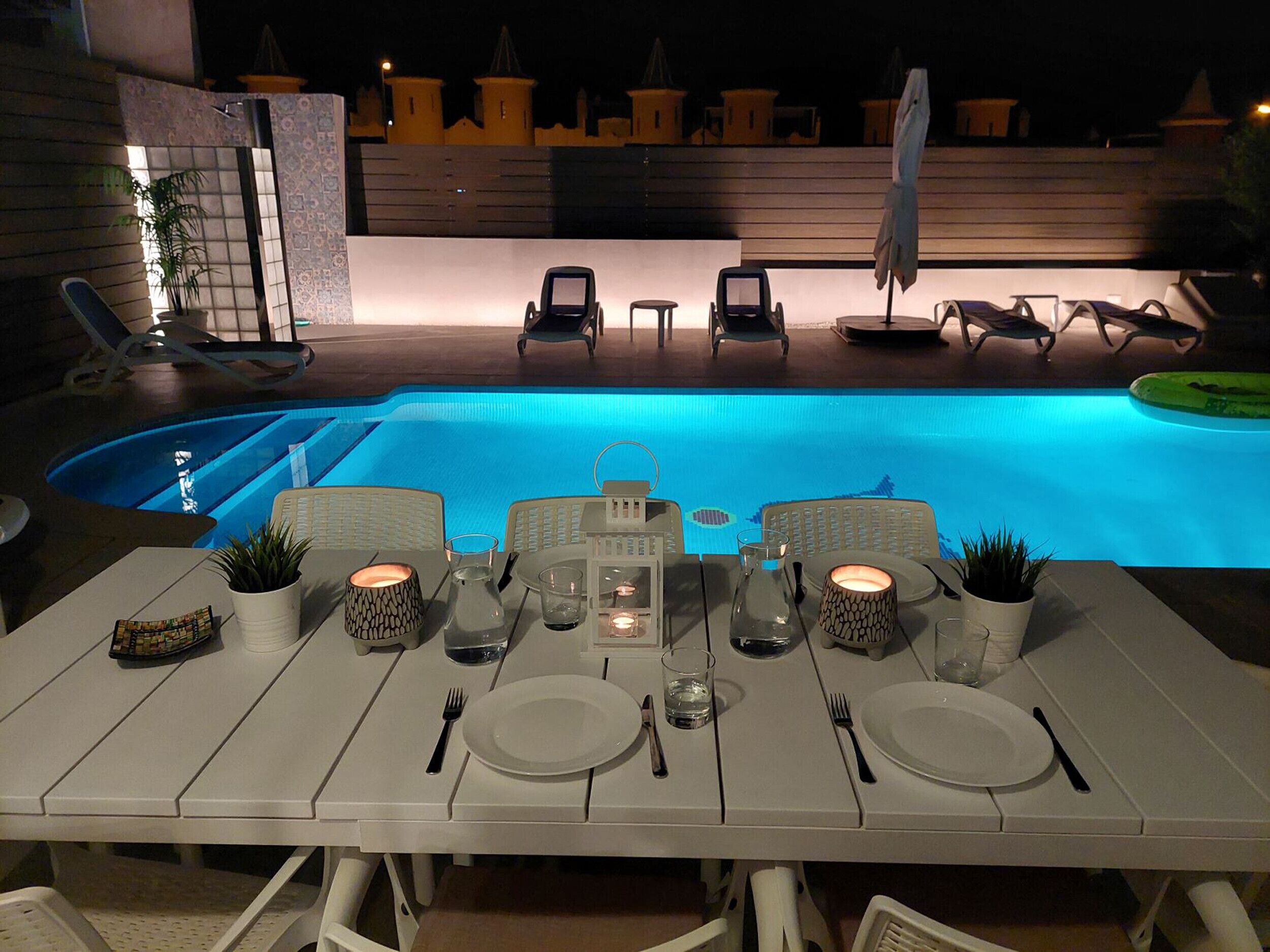 Ein Esstisch für zwei Personen mit Pool im Hintergrund.