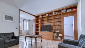 A living room with a sofa, a coffee table, a television, and a bookshelf. - SUNNY Ghetto canal (Venezia)