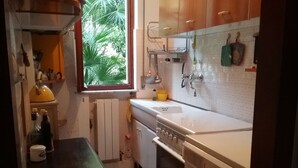 A compact kitchen with a built-in oven, a washing machine, and a window with a view of greenery. - Apartment with sea view, 5 minutes from the beach (Finale Ligure)