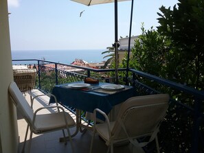 Un balcon avec une table dressée pour deux personnes, donnant sur la mer.