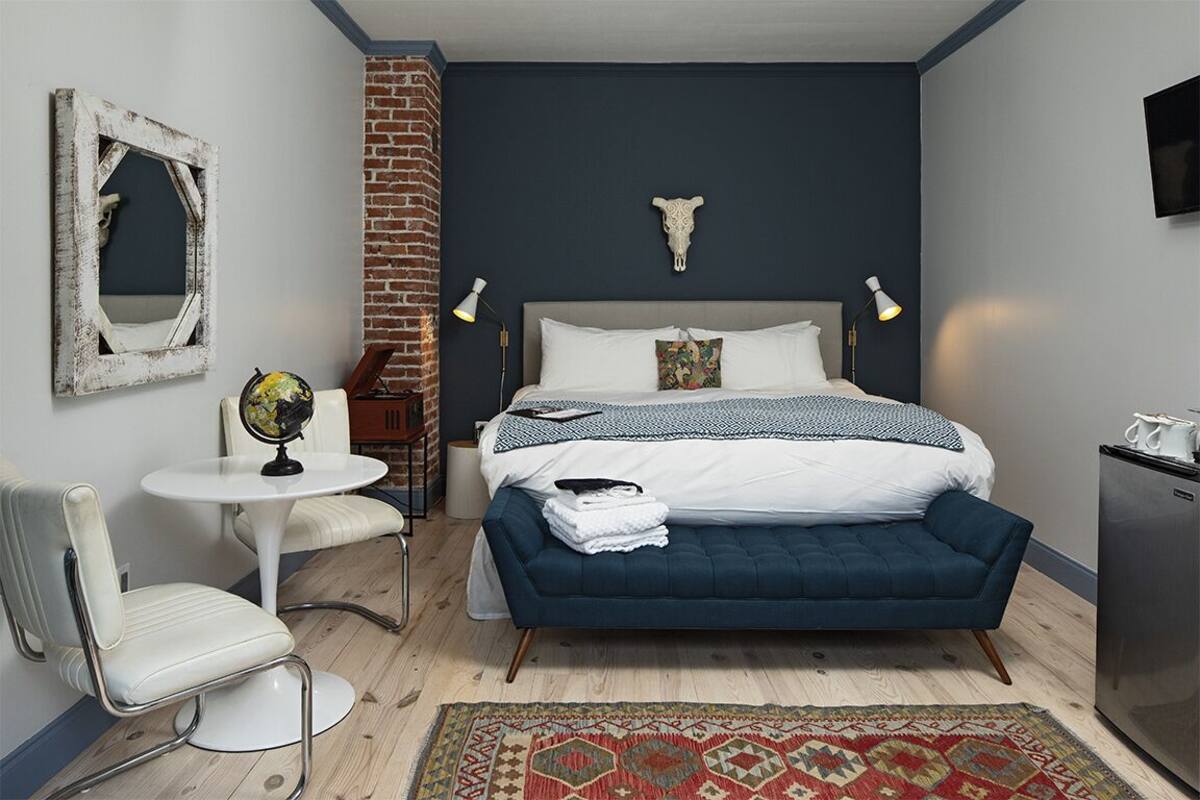 A bedroom with a bed, a desk, a chair, a globe, a lamp, and a television.