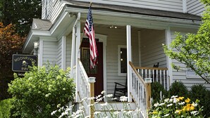 A white building with a porch, an American flag, and a sign for Moonriver Inn. - Moonriver Inn (Narrowsburg)