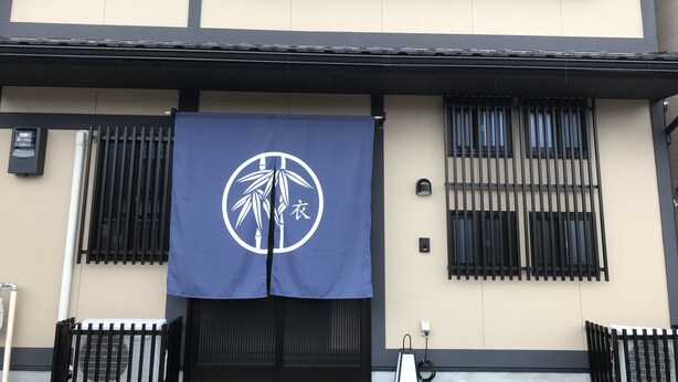 Un bâtiment doté d’un auvent bleu orné d’un logo blanc, de barreaux noirs aux fenêtres et d’une façade beige.