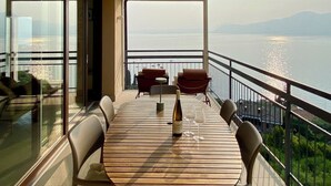 Ein Balkon mit Tisch, Stühlen und einer Weinflasche.