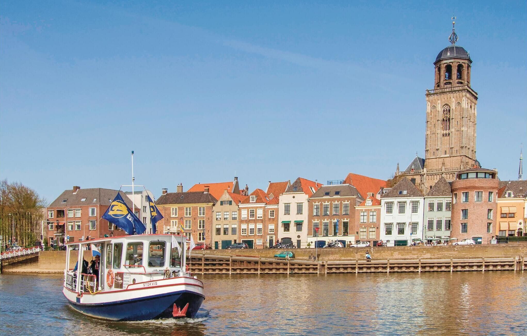 A boat with a blue and white color scheme, docked near a historic building with a prominent tower.