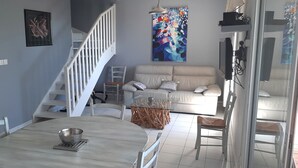 A living room with a staircase, a sofa set, a dining table with a bowl, and a large abstract painting on the wall. - * All comforts, private swimming pool, full sea view * (Fleury)