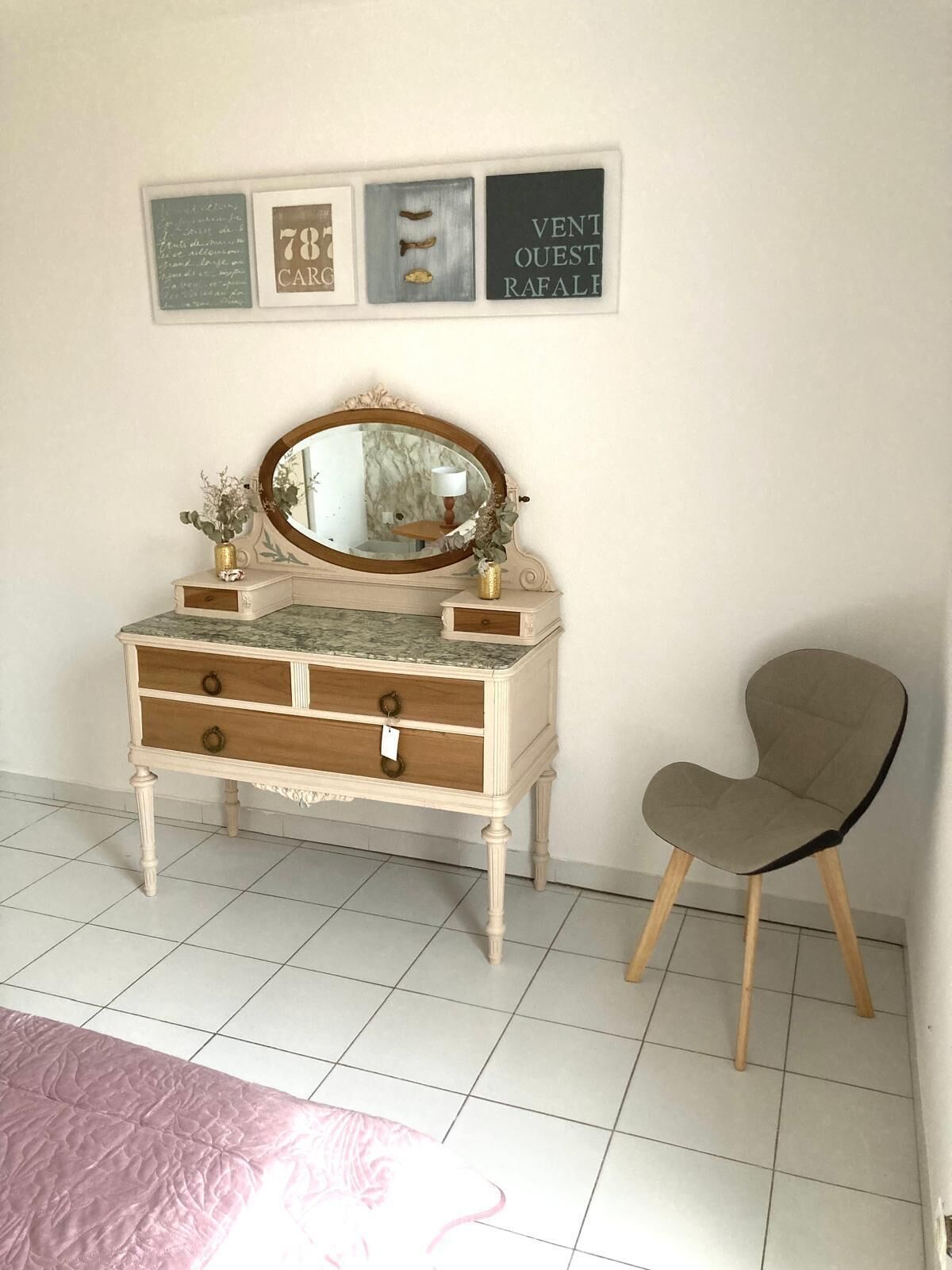 Une pièce comprenant une coiffeuse, une chaise et trois objets encadrés accrochés au mur.