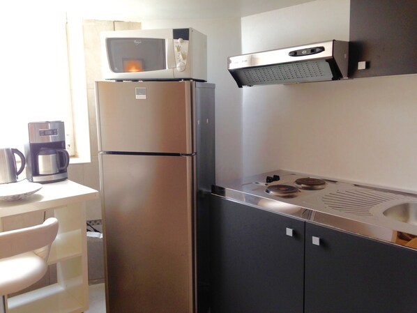 A kitchen with a refrigerator, microwave, coffee maker, and a stove.