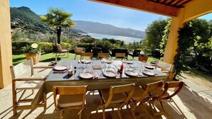 An outdoor dining area with a table set for six, overlooking a scenic view of the ocean and hills. - CHARMING VILLA,UP-MARKET,PANORAMIC SEA VIEW, 3MN WALK TO A BEAUTIFUL SAND BEACH (Casaglione)