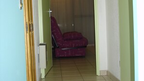 A room with a red chair, a wooden door, and a tiled floor.