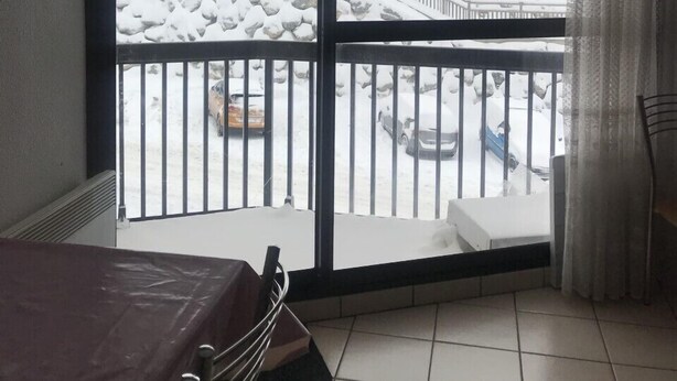 A room with a view of a snowy outdoor area through a large window.