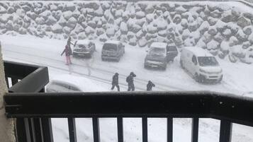 Un parking enneigé avec des voitures et une personne qui marche.