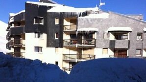 A multi-story building with balconies and a snow-covered roof.