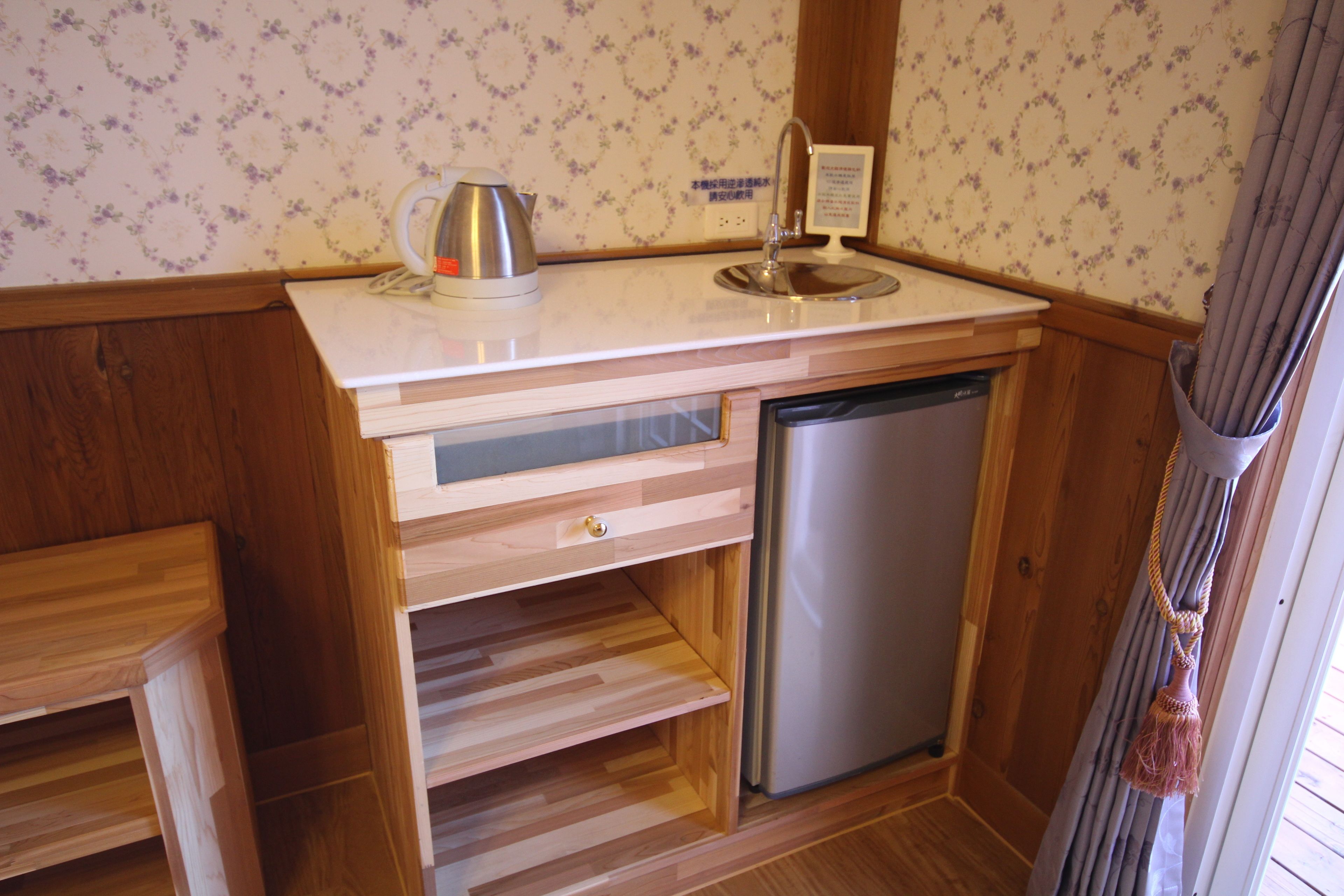 Una kitchenette compacta con cafetera de acero inoxidable, un lavamanos y un lavavajillas.