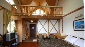 A room with a loft bed, wooden beams, a television, and a small desk. - Vienna B and B (Ren'ai)