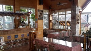 A restaurant with wooden walls, large windows, and checkered tablecloths. - Vienna B and B (Ren'ai)