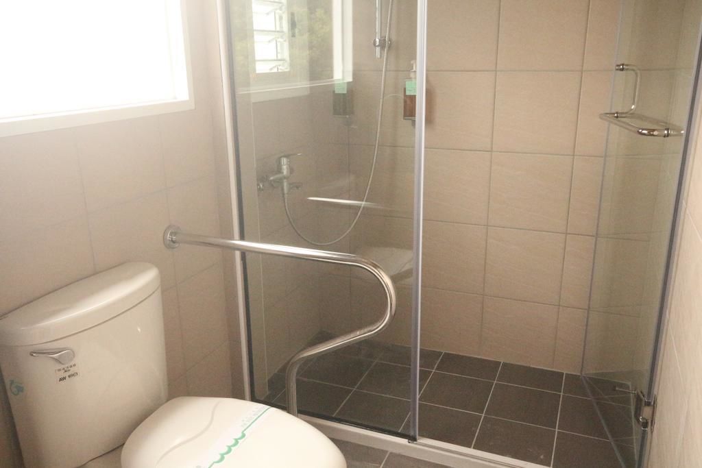 Un baño con ducha de mampara de vidrio, inodoro blanco y paredes con azulejos.
