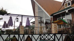 A building with a tiled roof, a balcony with purple umbrellas, and a white and black facade. - Vienna B and B (Ren'ai)