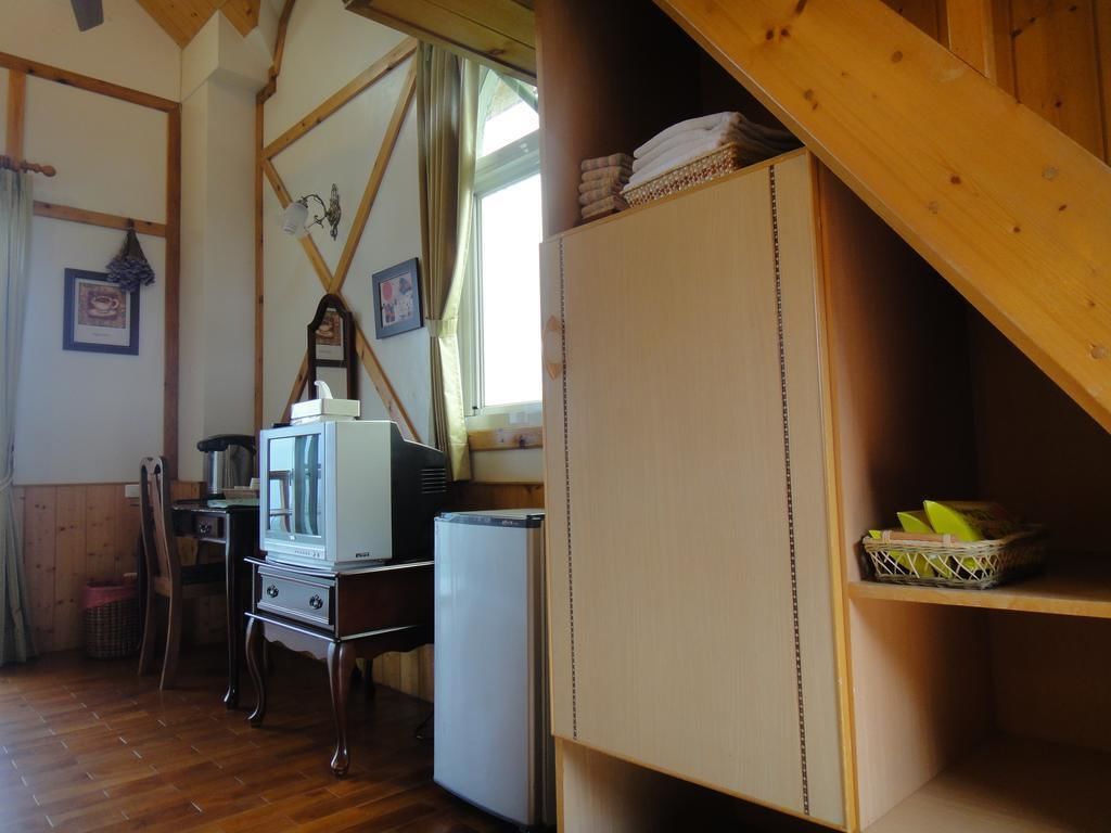 A rustic room with wooden beams, a wooden cabinet, a television, and a refrigerator.