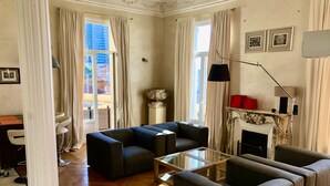 A spacious living room with a sectional sofa, a glass coffee table, and a fireplace. - Flat in Beausoleil, Monaco: double glazing, terrace, sea view & paying parking (Beausoleil)