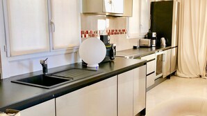 A modern kitchen with a black countertop, stainless steel appliances, and a large white spherical object on the counter. - Flat in Beausoleil, Monaco: double glazing, terrace, sea view & paying parking (Beausoleil)