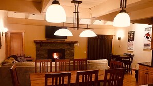 A cozy living area with a fireplace, wooden furniture, and a stone wall. - Year round fun luxury location steps to Village, close to all outdoor activities (Mammoth Lakes)