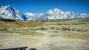A person relaxing by a natural hot spring with a mountainous backdrop. - Year round fun luxury location steps to Village, close to all outdoor activities (Mammoth Lakes)