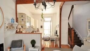 Ein gemütliches Wohnzimmer mit Kamin, eine Essecke mit Stühlen und Tisch sowie eine Treppe zu einer weiteren Ebene.