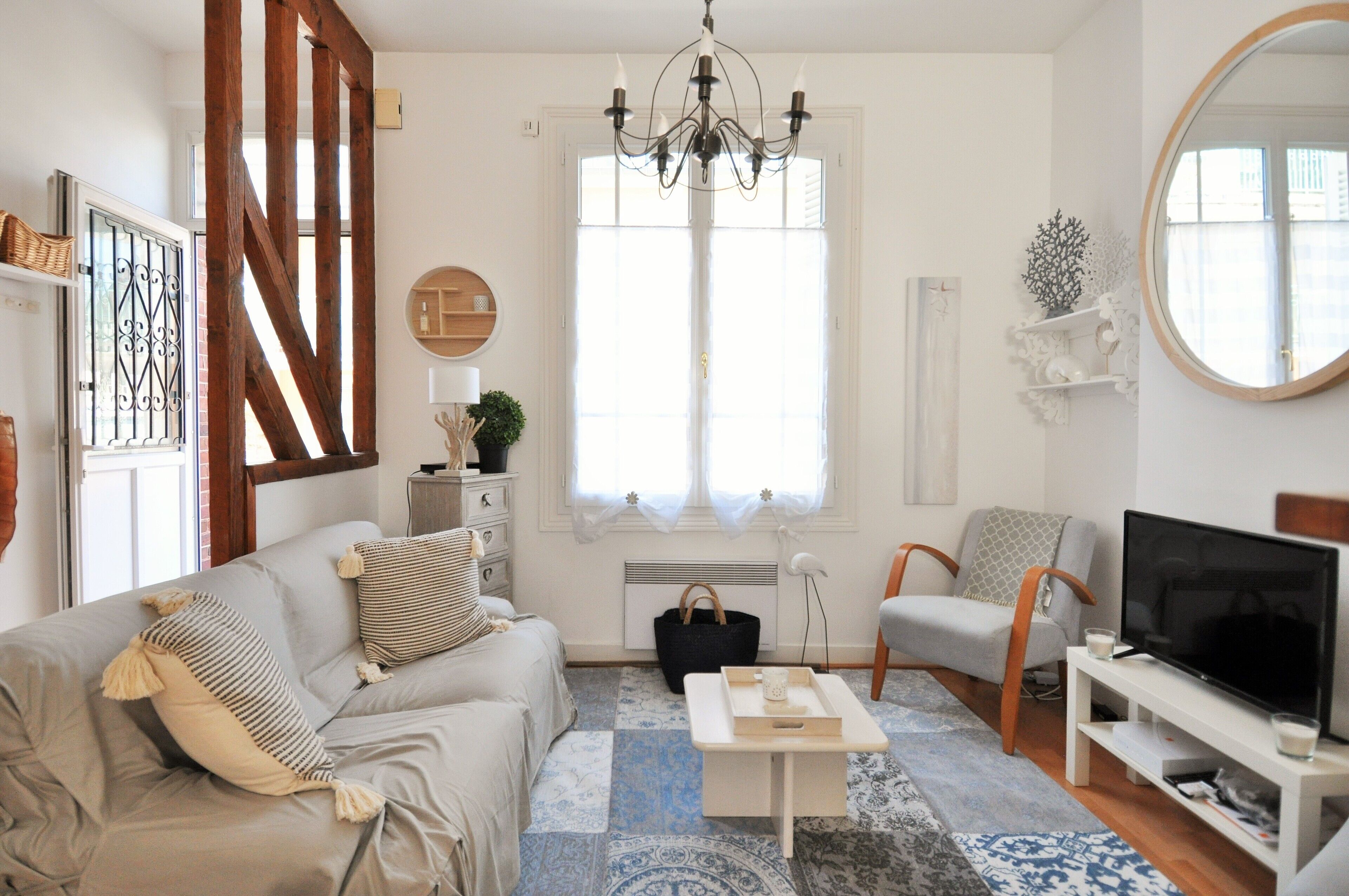 A living room with a sofa, coffee table, TV, and a large window with curtains.