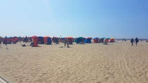 Ein sandiger Strand mit bunten Strandsonnenschirmen und Zelten.