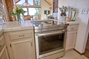 A kitchen with a stainless steel oven, white cabinets, and a large window providing a view of the outdoors. - Panoramic Views From This Monthly Rental in Cambria! Stunning! (Cambria)