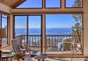 Una stanza con ampie porte scorrevoli in vetro che danno su un balcone vista oceano.