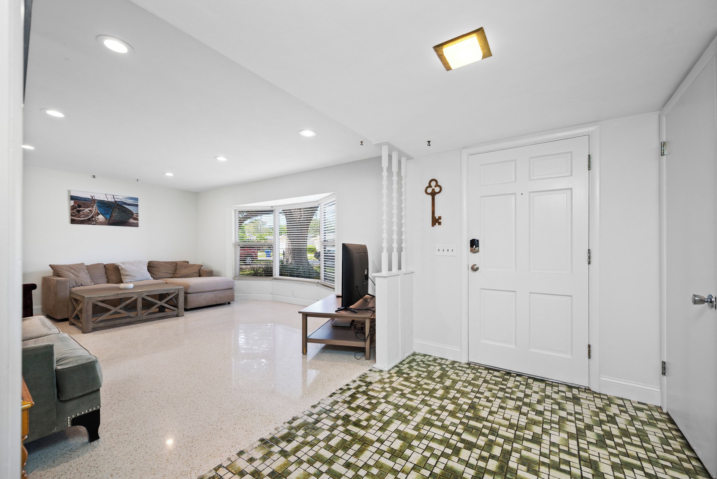 A spacious living area with a sofa set, a television, and a patterned rug.