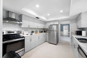 A modern kitchen with white cabinetry, stainless steel appliances, and a marble countertop. - Spacious 3 Bedroom 2 Bath Walk to Eagle Lake Park Fenced Yard (Clearwater)