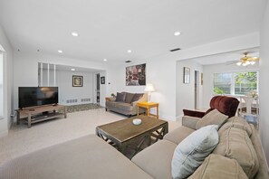 Una sala de estar moderna con televisor de pantalla plana, un sofá, una mesa de centro y una zona de comedor con mesa y sillas.